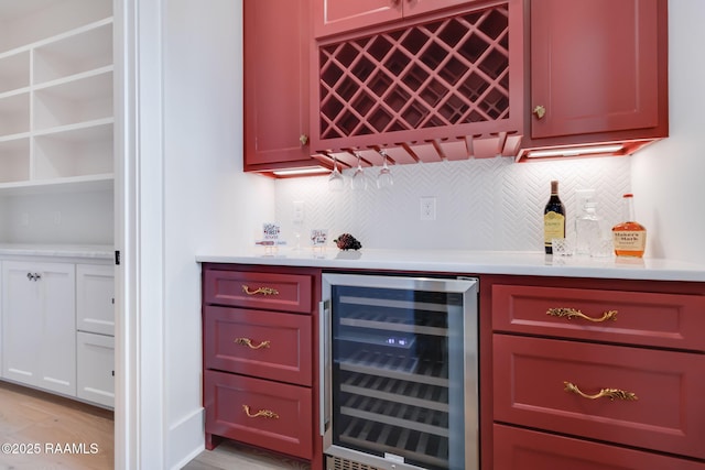 bar with a bar, light wood-style flooring, backsplash, and wine cooler