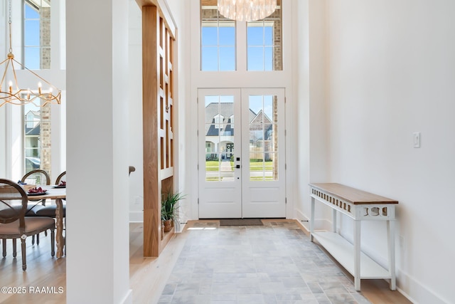 entryway featuring baseboards, a high ceiling, and an inviting chandelier