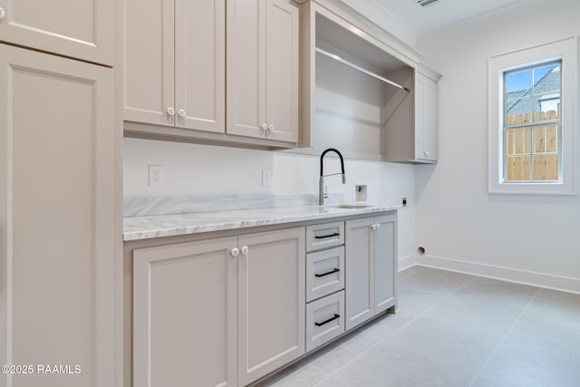 bar with a sink, baseboards, and light tile patterned flooring