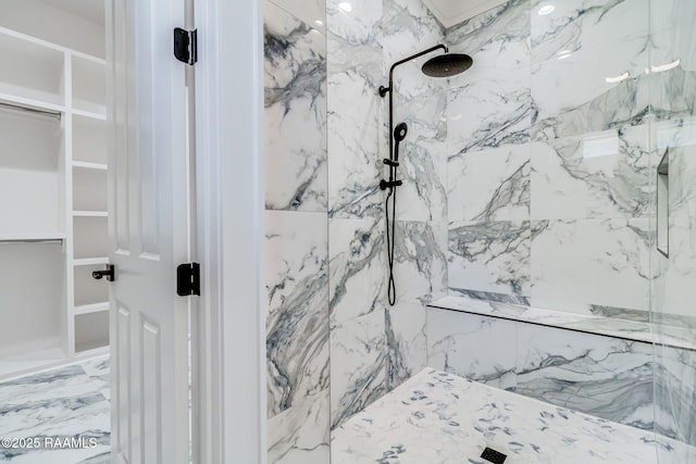 bathroom featuring a marble finish shower and a walk in closet
