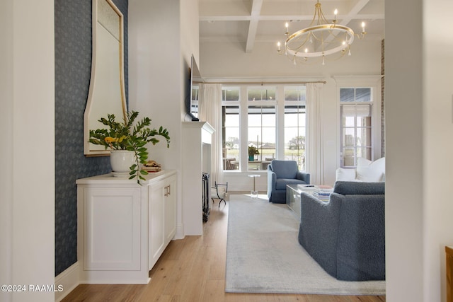 living room with beam ceiling, light hardwood / wood-style floors, an inviting chandelier, and coffered ceiling