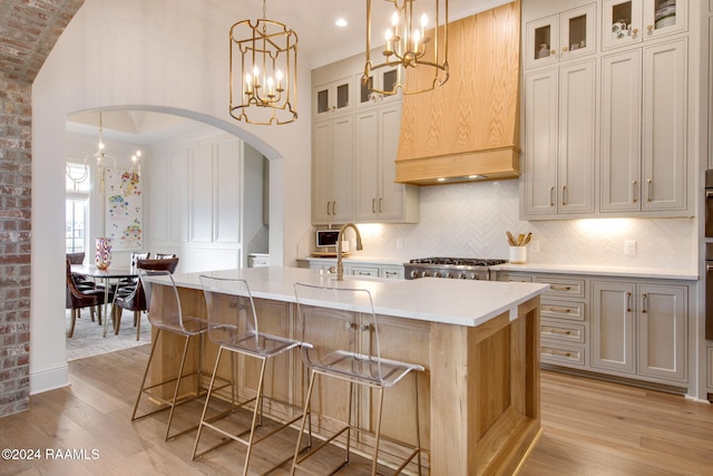 kitchen featuring stainless steel range, sink, light hardwood / wood-style flooring, and an island with sink