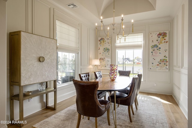 dining space with vaulted ceiling, light hardwood / wood-style flooring, a chandelier, and plenty of natural light