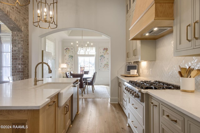 kitchen featuring a center island with sink, light hardwood / wood-style floors, custom range hood, and an inviting chandelier