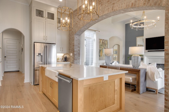 kitchen featuring high vaulted ceiling, light wood-type flooring, an island with sink, and appliances with stainless steel finishes