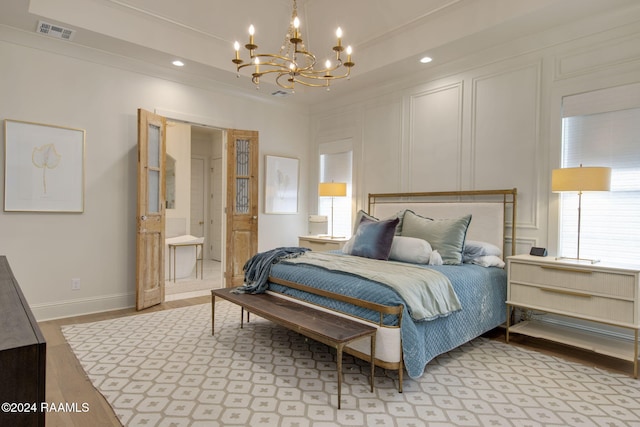 bedroom with ensuite bath, crown molding, light hardwood / wood-style floors, and a notable chandelier