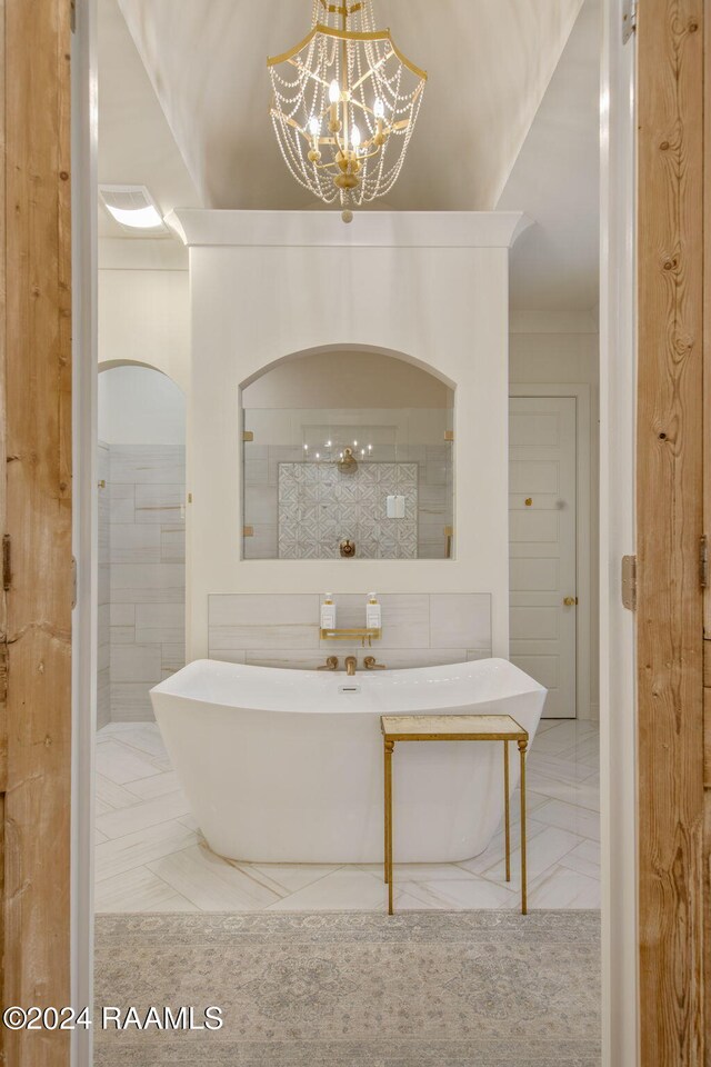 bathroom featuring a notable chandelier and a bath