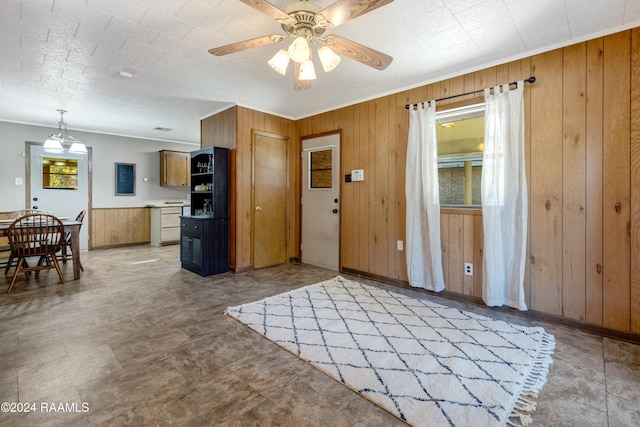 interior space featuring ceiling fan, crown molding, and wooden walls