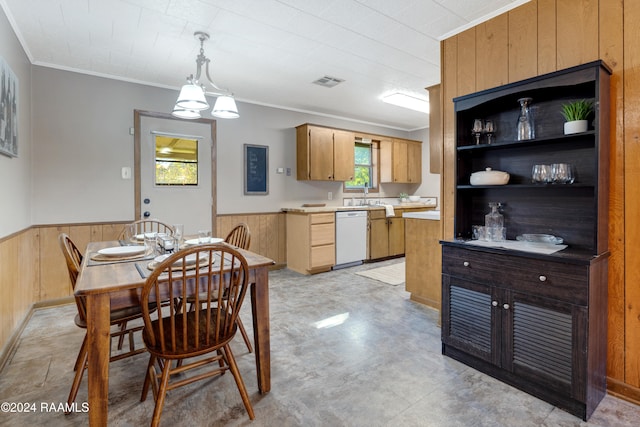 dining space featuring crown molding, wooden walls, and sink