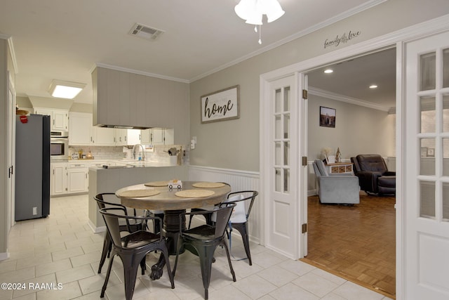 dining space with crown molding, sink, and light parquet floors