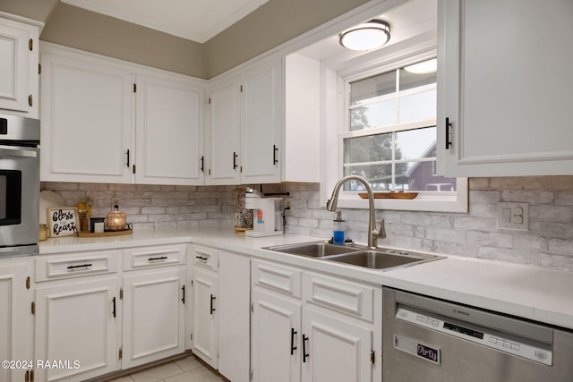 kitchen featuring backsplash, stainless steel appliances, sink, light tile patterned floors, and white cabinetry