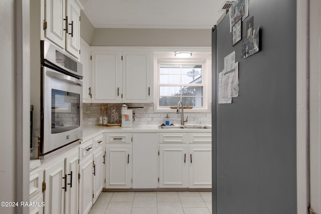 kitchen featuring stainless steel oven, sink, fridge, decorative backsplash, and white cabinets