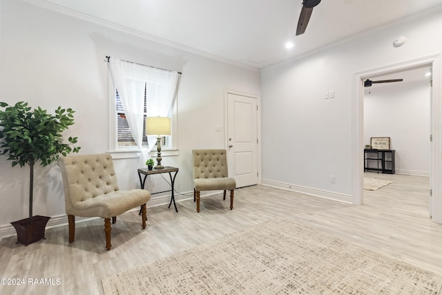 living area with light hardwood / wood-style floors, ceiling fan, and ornamental molding