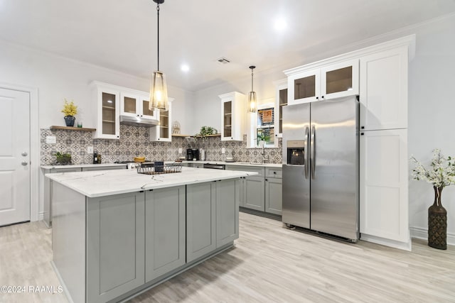 kitchen featuring stainless steel refrigerator with ice dispenser, light stone counters, decorative light fixtures, a center island, and gray cabinets