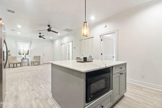 kitchen featuring black microwave, light hardwood / wood-style flooring, pendant lighting, gray cabinets, and a kitchen island