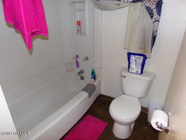 bathroom featuring hardwood / wood-style flooring, shower / bathtub combination, and toilet