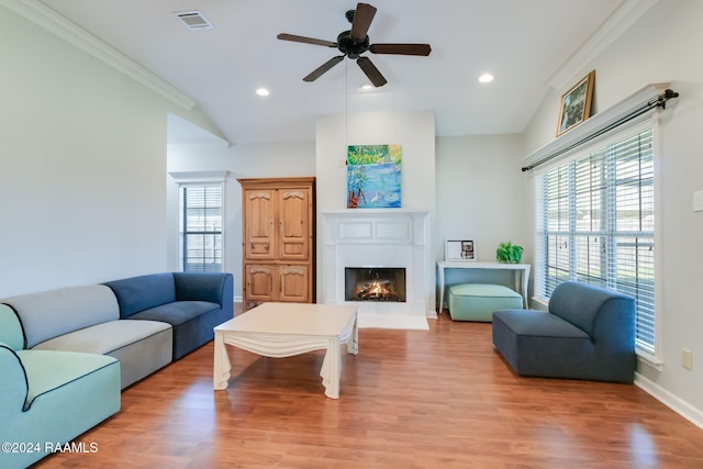 living room with ceiling fan, light hardwood / wood-style floors, ornamental molding, and vaulted ceiling