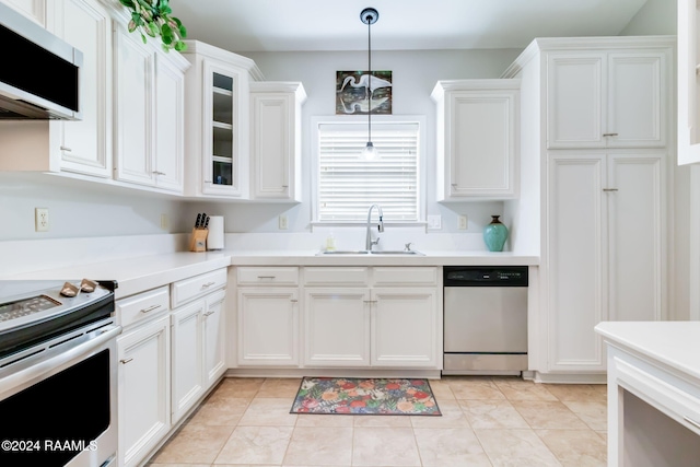 kitchen featuring appliances with stainless steel finishes, sink, light tile patterned floors, decorative light fixtures, and white cabinetry