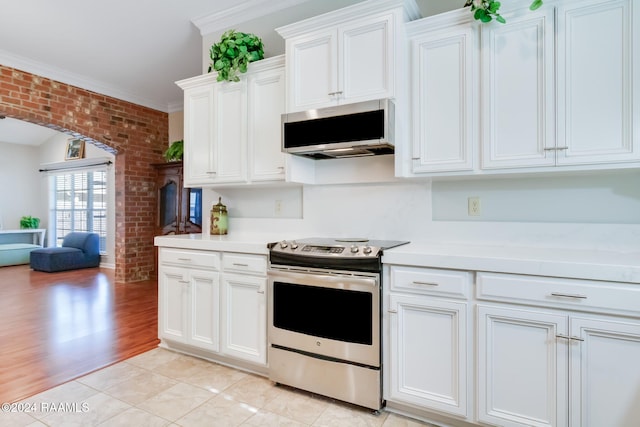 kitchen featuring brick wall, white cabinetry, appliances with stainless steel finishes, and light hardwood / wood-style flooring