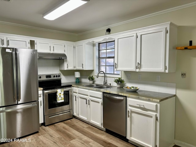 kitchen with appliances with stainless steel finishes, light wood-type flooring, ornamental molding, sink, and white cabinets