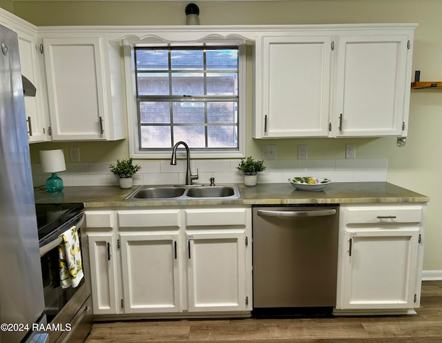 kitchen featuring white cabinets, sink, dark hardwood / wood-style floors, range hood, and appliances with stainless steel finishes