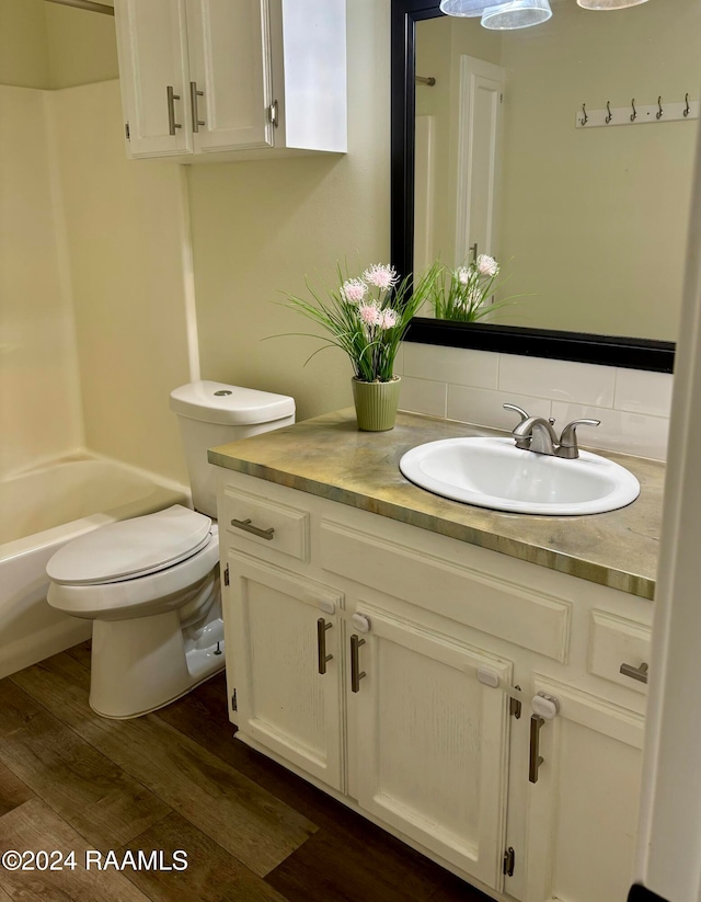 full bathroom with hardwood / wood-style floors, vanity, toilet, and shower / bath combination