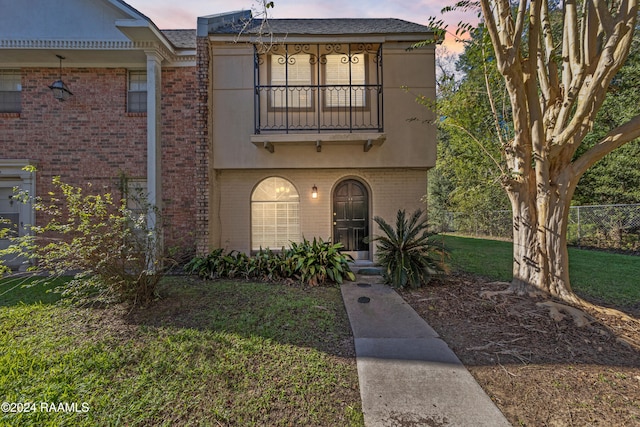 view of front of property with a yard and a balcony