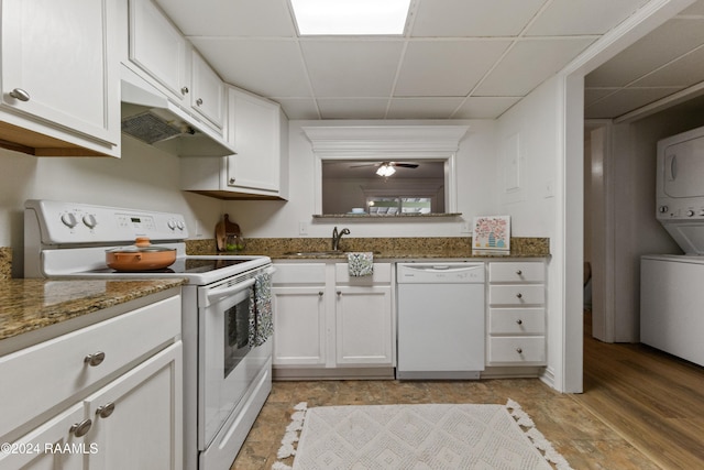 kitchen with a drop ceiling, white appliances, white cabinets, light wood-type flooring, and stacked washer / drying machine