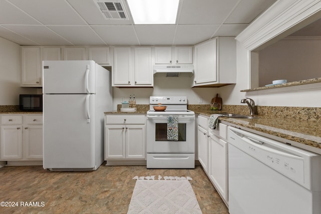 kitchen with a paneled ceiling, white cabinets, stone countertops, and white appliances