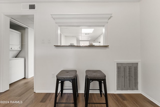 dining room featuring hardwood / wood-style floors, crown molding, and stacked washer and clothes dryer