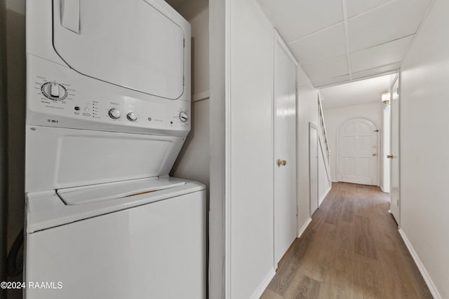 clothes washing area featuring stacked washer and dryer and hardwood / wood-style flooring