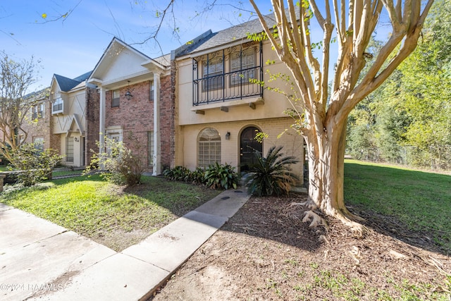 view of front of property with a balcony and a front lawn