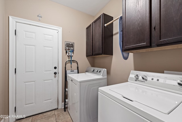 clothes washing area with light tile patterned flooring, cabinets, and washing machine and dryer