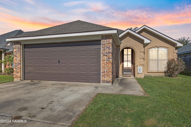 ranch-style house featuring a garage and a yard