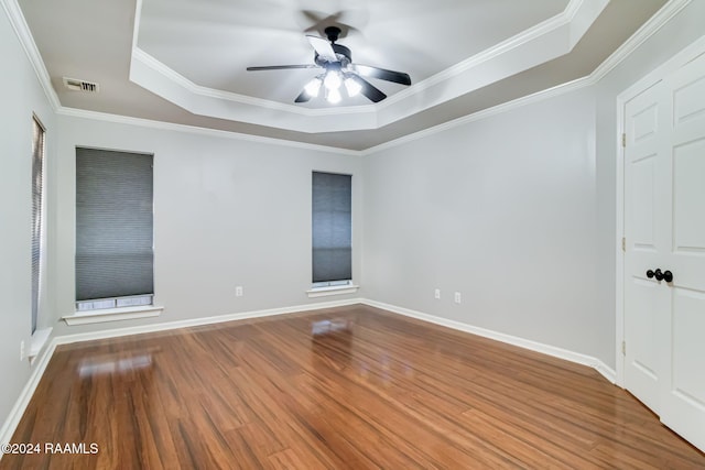 empty room with hardwood / wood-style floors, ceiling fan, crown molding, and a tray ceiling