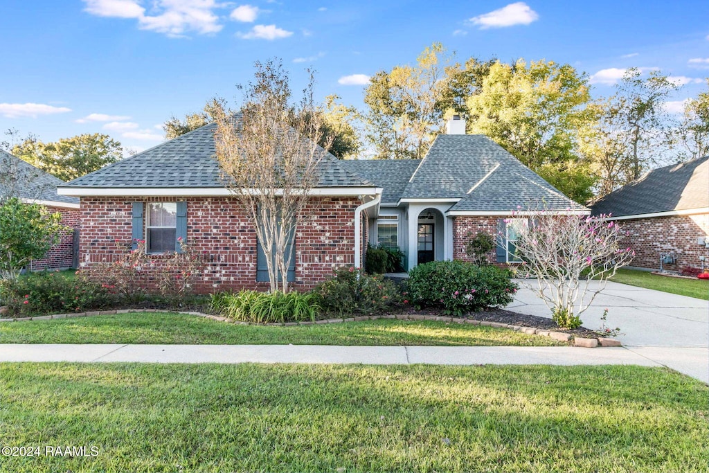 103 River Birch Dr, Lafayette, LA 70508 - view of front of property featuring a front yard, a shingled roof, a chimney, concrete driveway, and brick siding