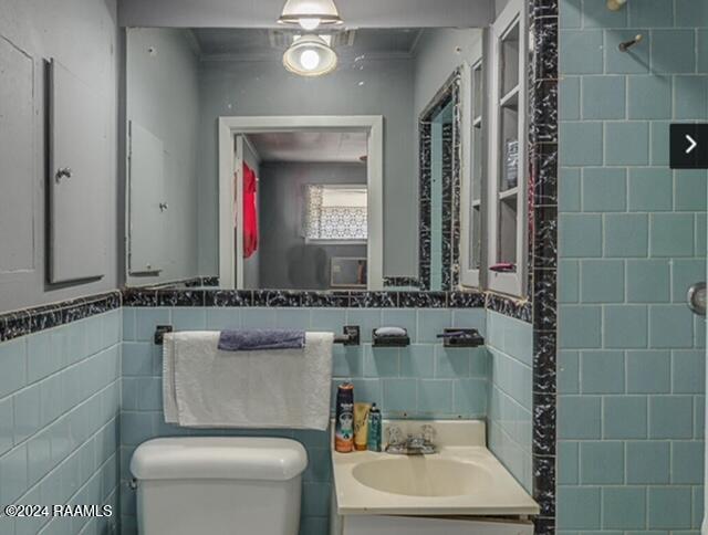 bathroom with vanity, toilet, and tile walls