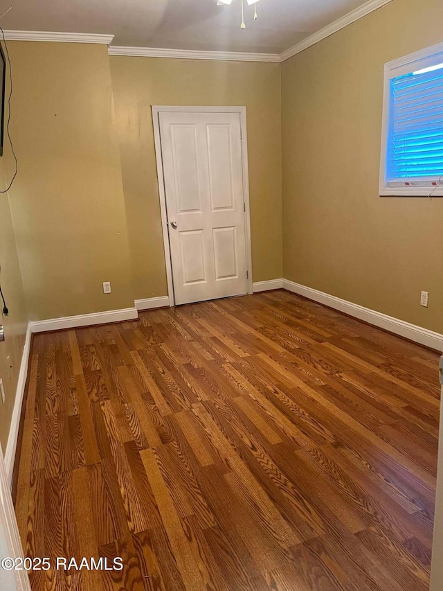 empty room featuring crown molding, baseboards, and wood finished floors