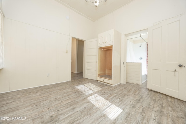 unfurnished bedroom with a high ceiling, light hardwood / wood-style flooring, and ornamental molding