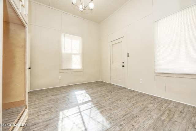 spare room with a chandelier, wood-type flooring, and crown molding