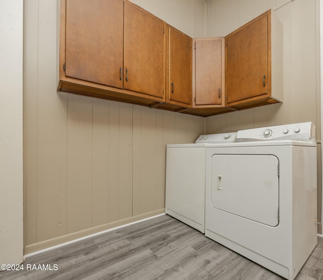 laundry room with separate washer and dryer, light hardwood / wood-style floors, and cabinets