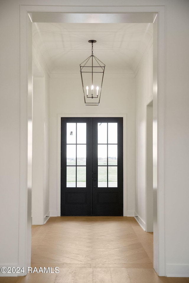 entryway featuring light hardwood / wood-style floors, french doors, ornamental molding, and an inviting chandelier