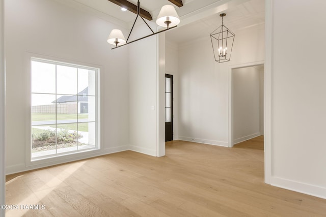 unfurnished dining area with beamed ceiling, an inviting chandelier, and light hardwood / wood-style flooring