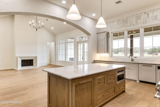 kitchen featuring stainless steel microwave, sink, a center island, hanging light fixtures, and plenty of natural light