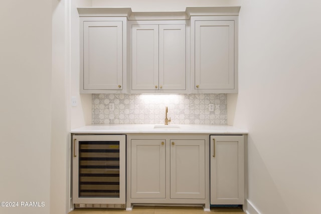 bar featuring tasteful backsplash, sink, and beverage cooler