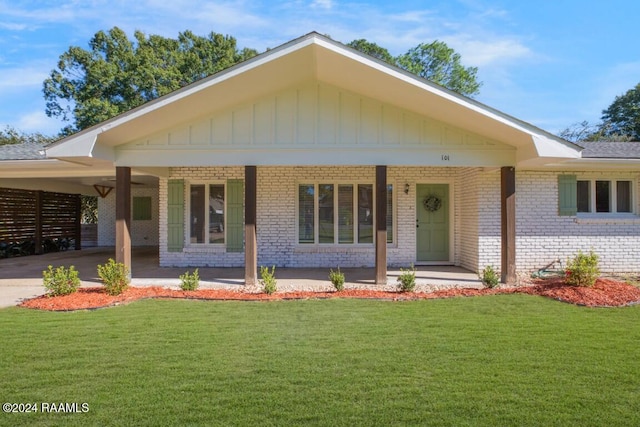 view of front facade featuring covered porch, a front yard, and a carport