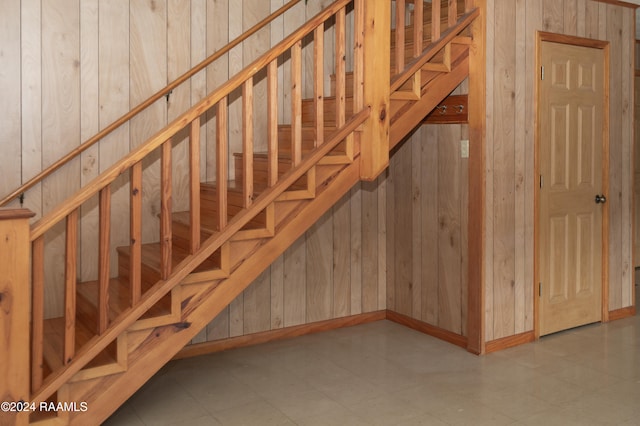 staircase featuring wooden walls