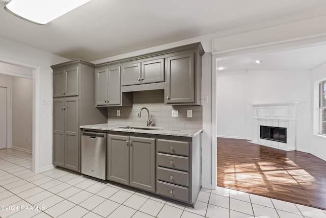 kitchen featuring gray cabinetry, dishwasher, backsplash, sink, and light wood-type flooring