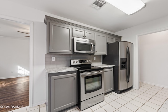 kitchen featuring gray cabinetry, ceiling fan, backsplash, and appliances with stainless steel finishes