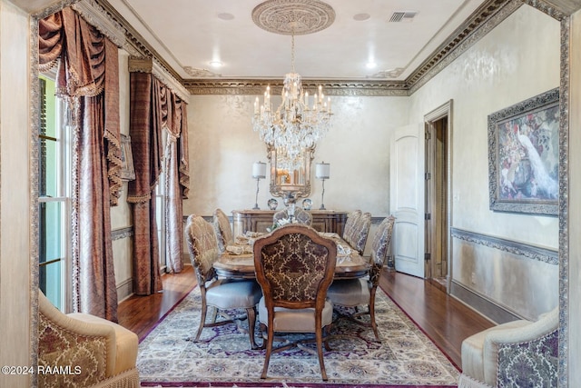 dining area featuring wood-type flooring, crown molding, and an inviting chandelier